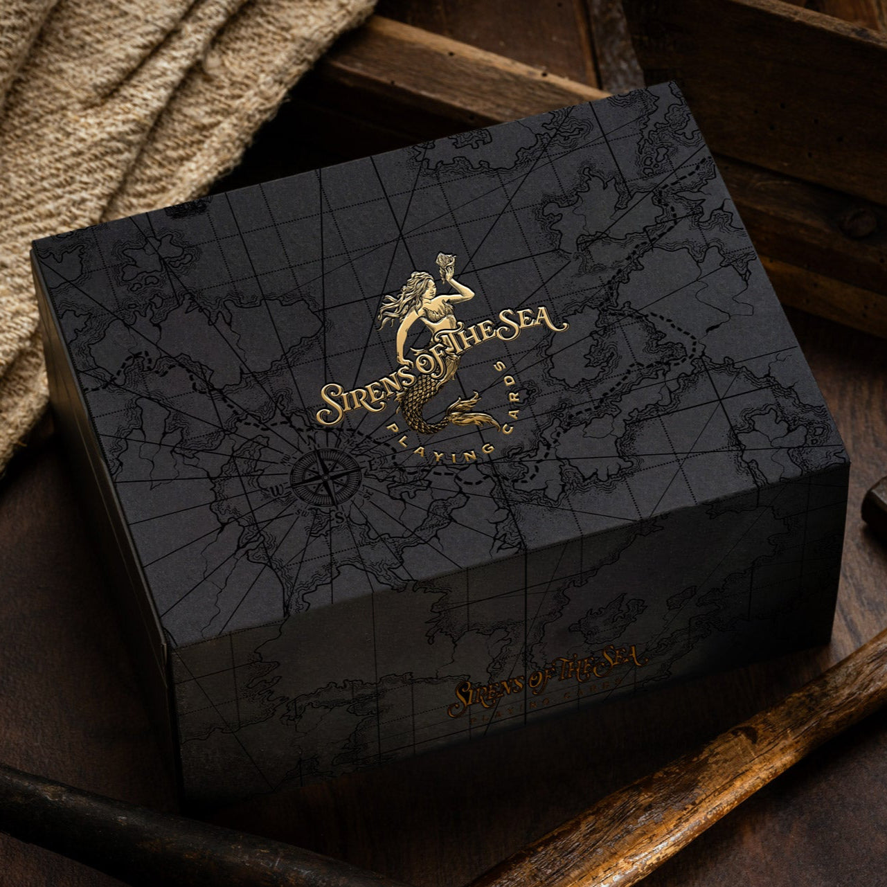 Black box with gold detailing featuring a logo and text, placed on a wooden surface.