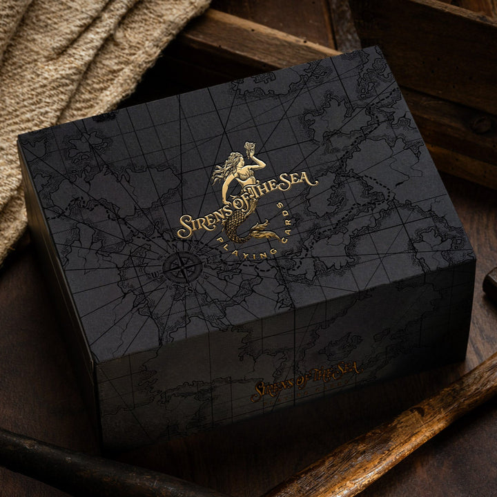 Black box with gold detailing featuring a logo and text, placed on a wooden surface.
