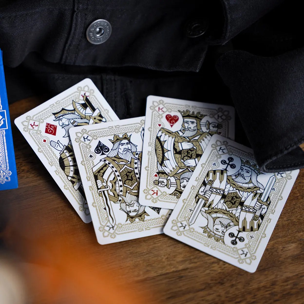 Eminence Blue Topaz playing cards featuring detailed king and queen designs on a wooden table