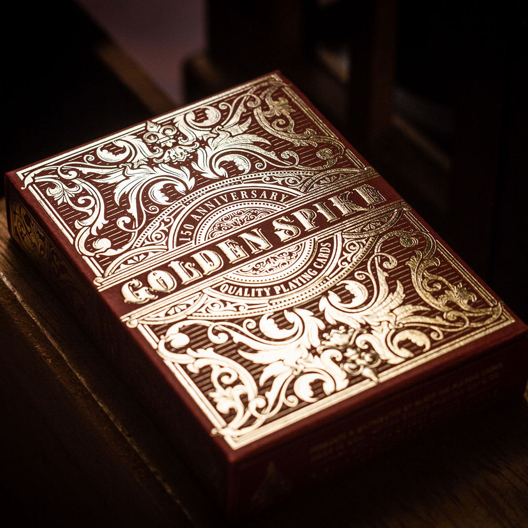 Golden Spike 150th Anniversary playing cards featuring ornate gold foil design on a red box