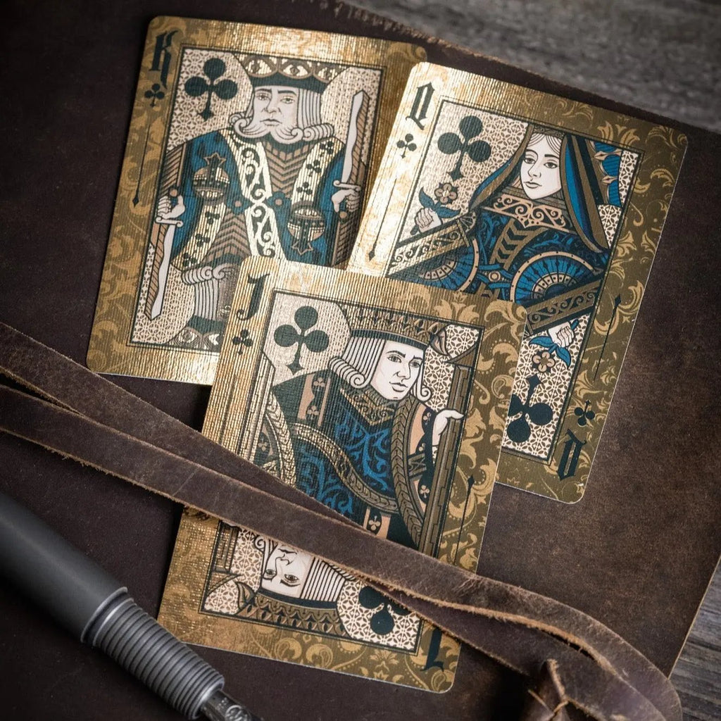 Stone Garden Second Edition playing cards featuring ornate King, Queen, and Jack designs on a wooden background