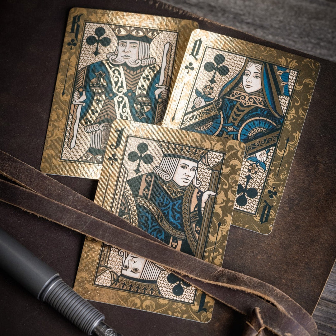 Stone Garden Second Edition playing cards featuring ornate King, Queen, and Jack designs on a wooden background