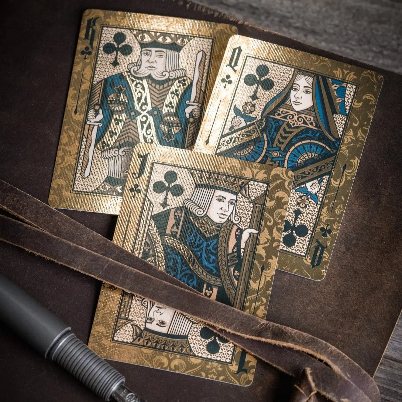 Stone Garden Second Edition playing cards featuring ornate King, Queen, and Jack designs on a wooden background