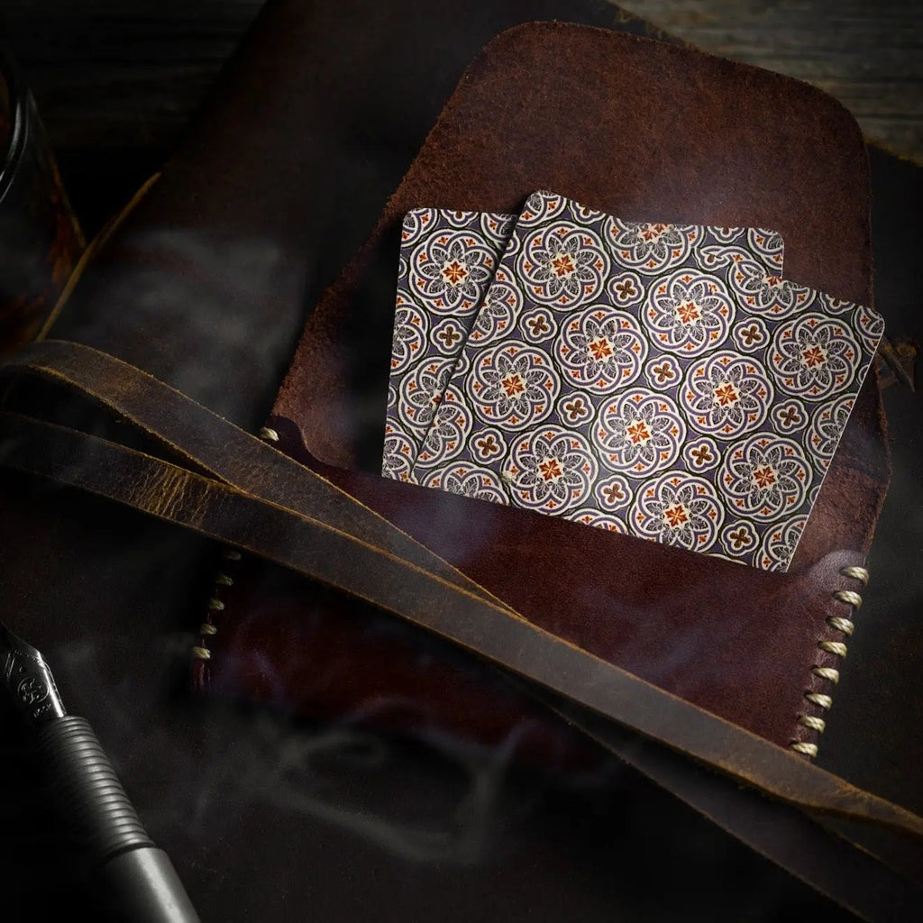 Stone Garden Second Edition playing cards with intricate floral design, placed on a brown leather surface