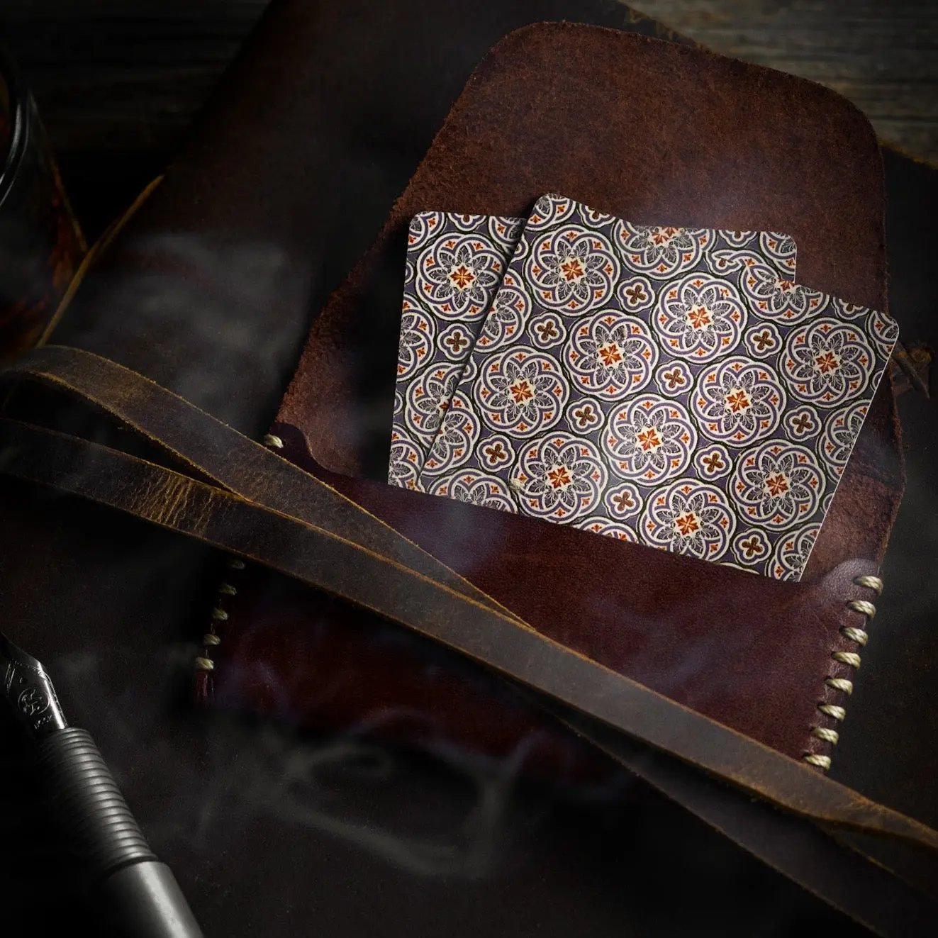 Stone Garden Second Edition playing cards with intricate floral design, placed on a brown leather surface